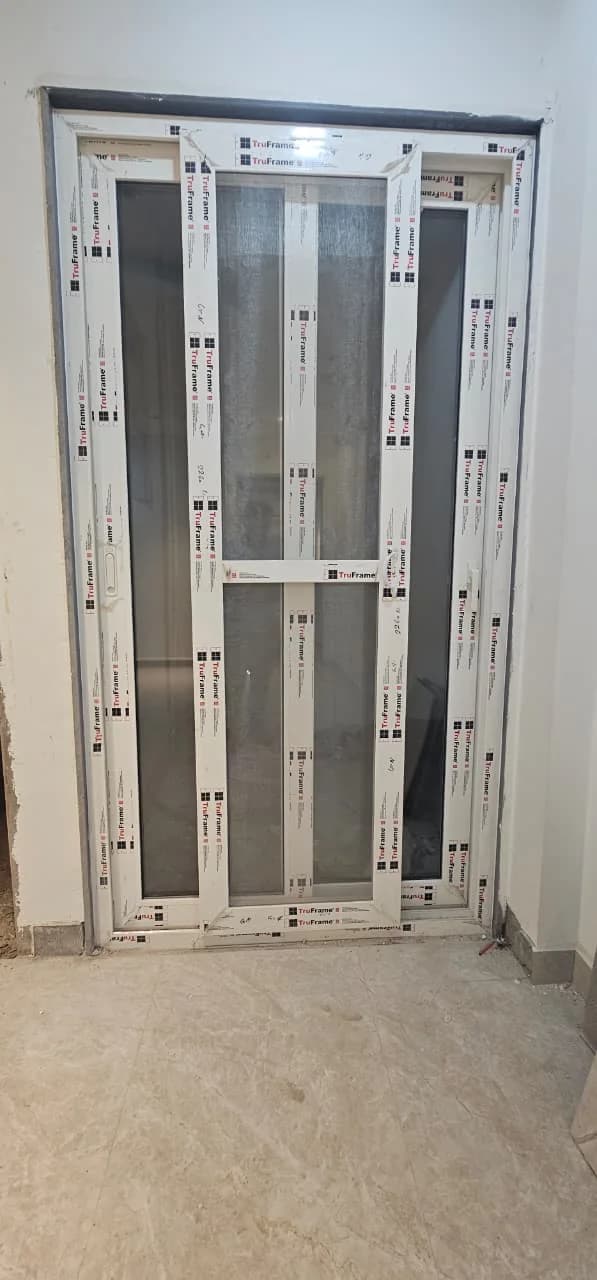 A white uPVC door frame fitted into a wall opening, protective film still on the profile