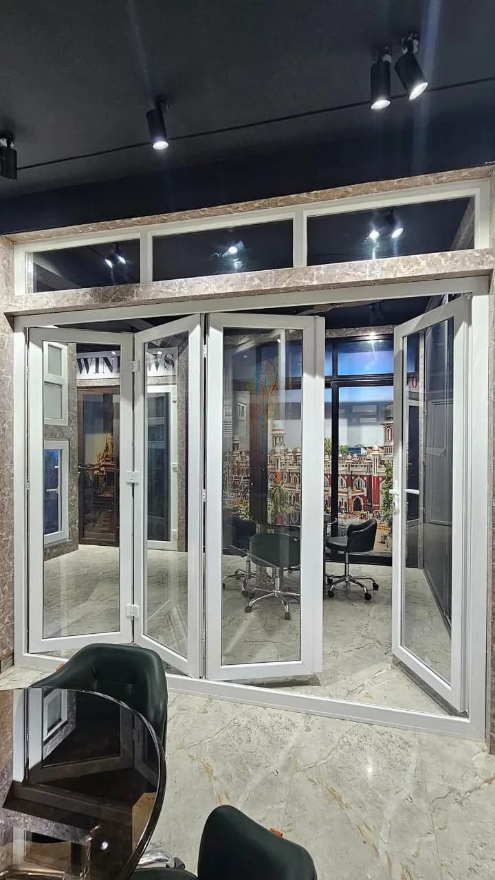 A white uPVC folding door, partly open, with fixed glazed transoms above, in a display room
