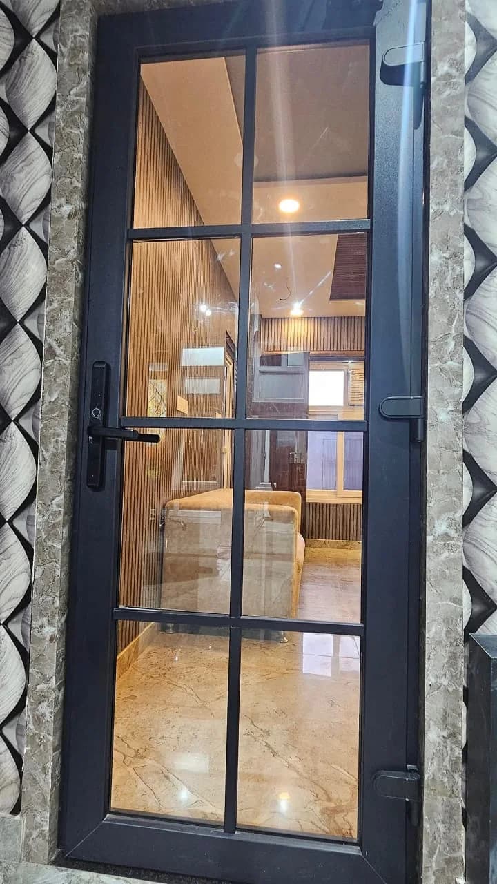 A dark-finished uPVC door with a glazing grid and a lever handle, set in a stone-clad wall